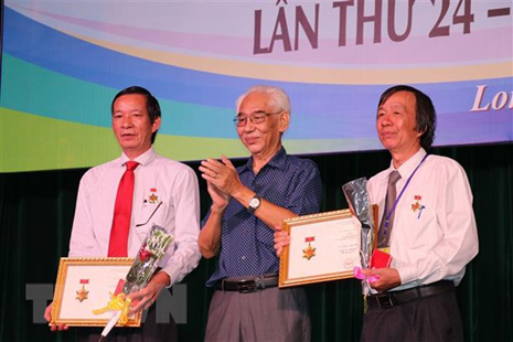 Họa sỹ Trần Khánh Chương (giữa) trong một buổi khai mạc triển lãm mỹ thuật. (Nguồn: TTXVN)